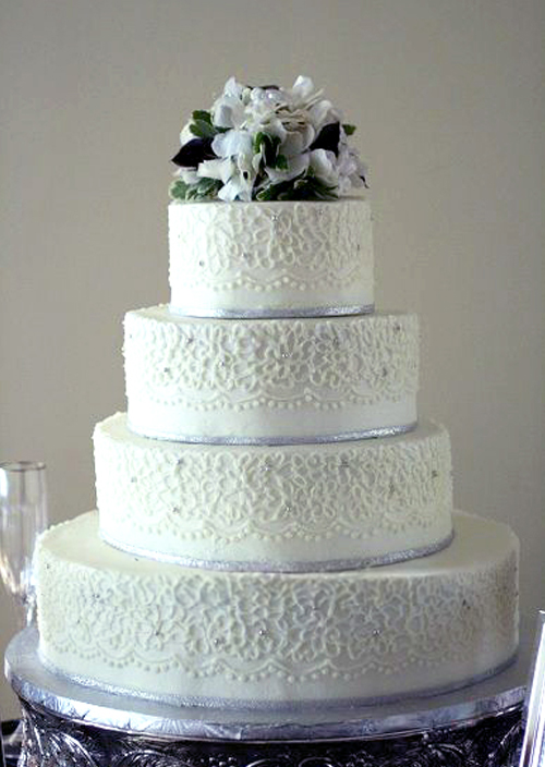 piped lace with silver bands wedding cake fresh flowers