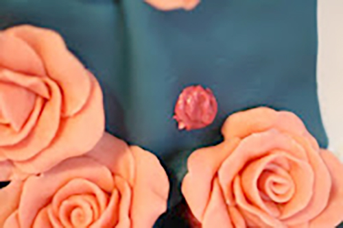 adding candy clay flowers to the rose-cake