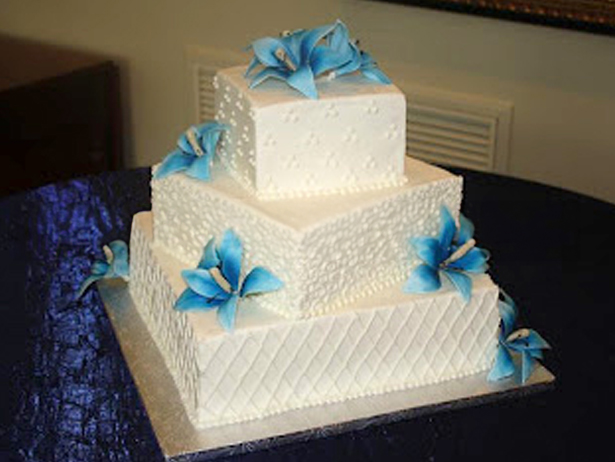 square offset wedding cake tiers with piped lace and blue daylilies