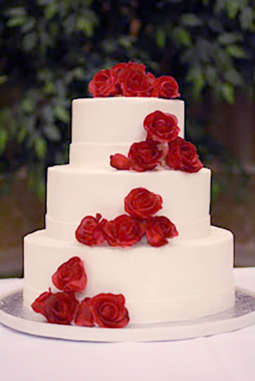 white wedding cake with red gumpaste roses