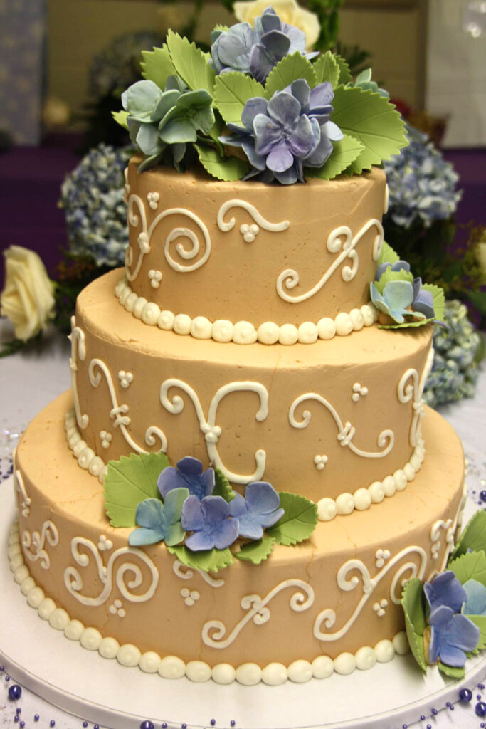 beige and white wedding cake with blue hydrangeas