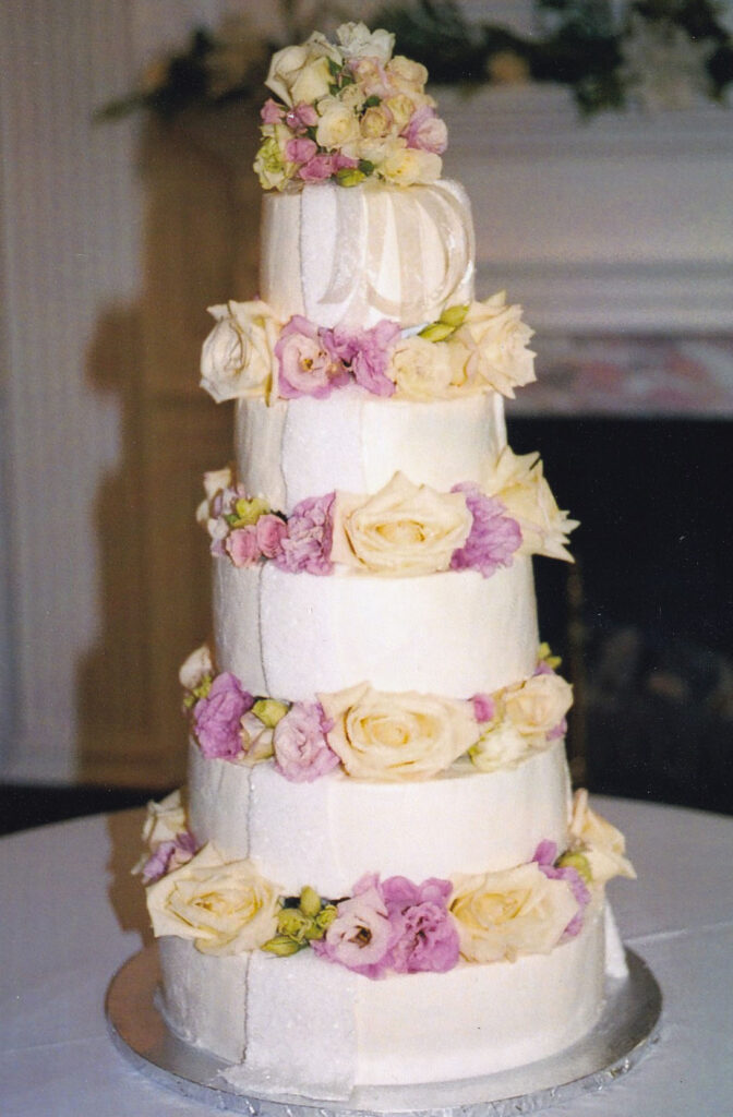 Pillars wedding cake with fresh roses between the pillars pink and ivory