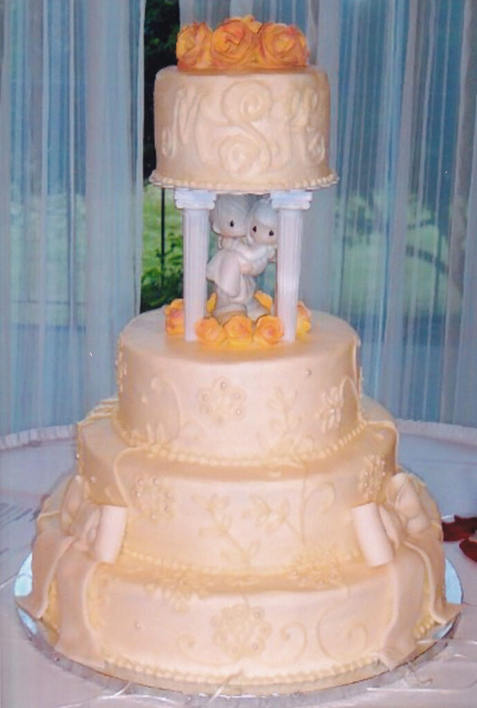 pale orange wedding cake with pillars and precious moments cake topper