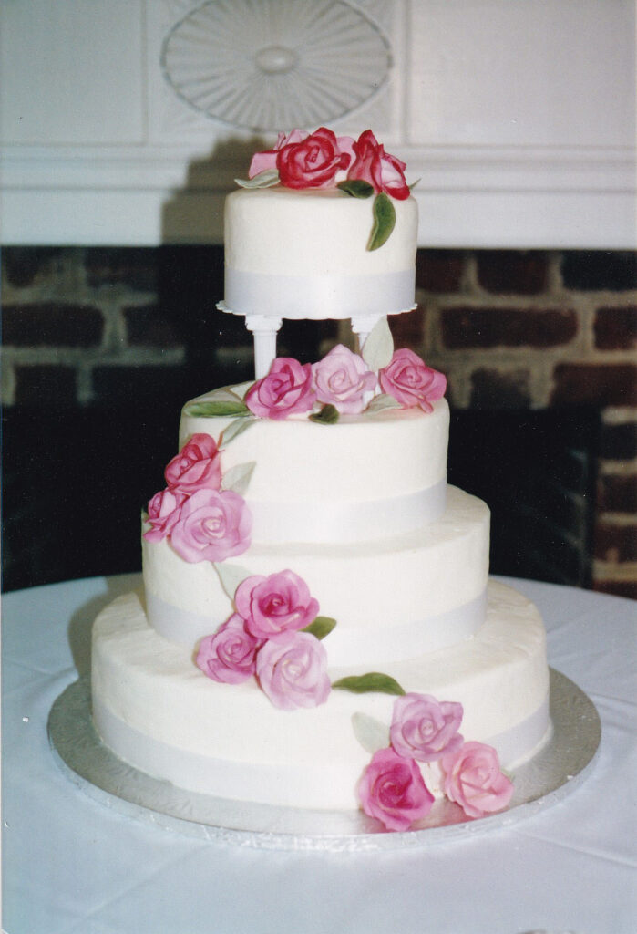 pillars wedding cake with white ribbon borders and pink gumpaste roses