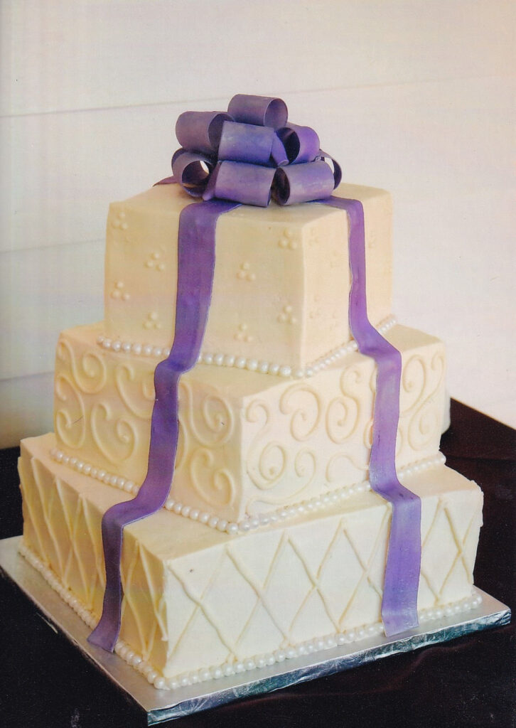 square pearls and swirls wedding cake with purple bow topper