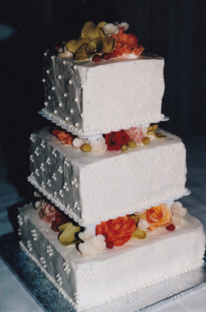 square swiss dots wedding cake with gumpaste flowers in orange and pink