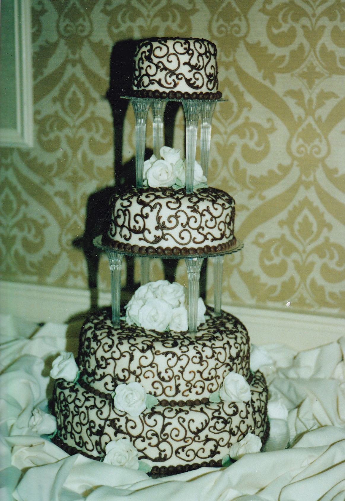tall pillared wedding cake with brown piping on hexagonal tiers and gumapste flowers