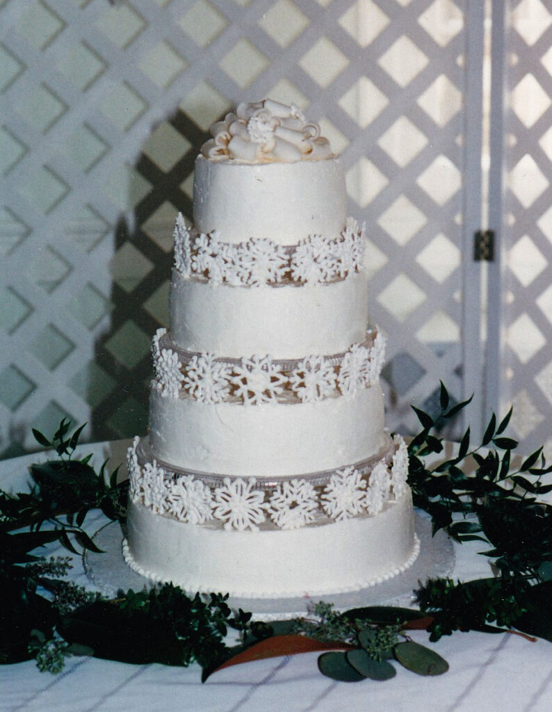 wedding cake with snowflakes between the tiers and fondant bow topper