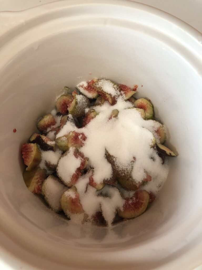 cut-up figs in a crock pot with sugar on them