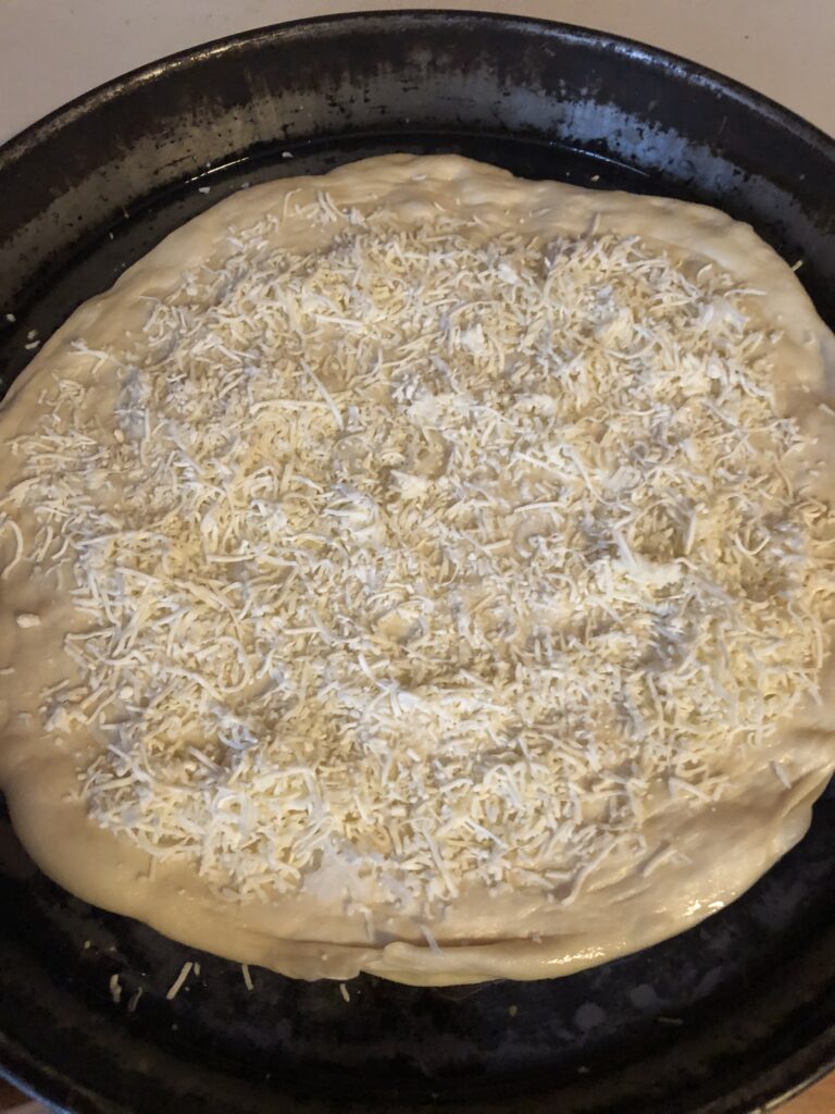 pizza dough in a pan with mozzarella on it