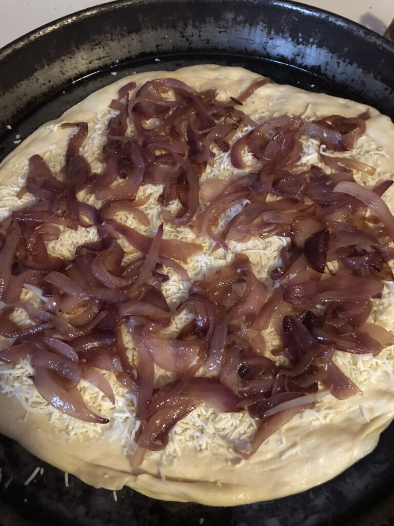 pizza dough in a pan with onions on it