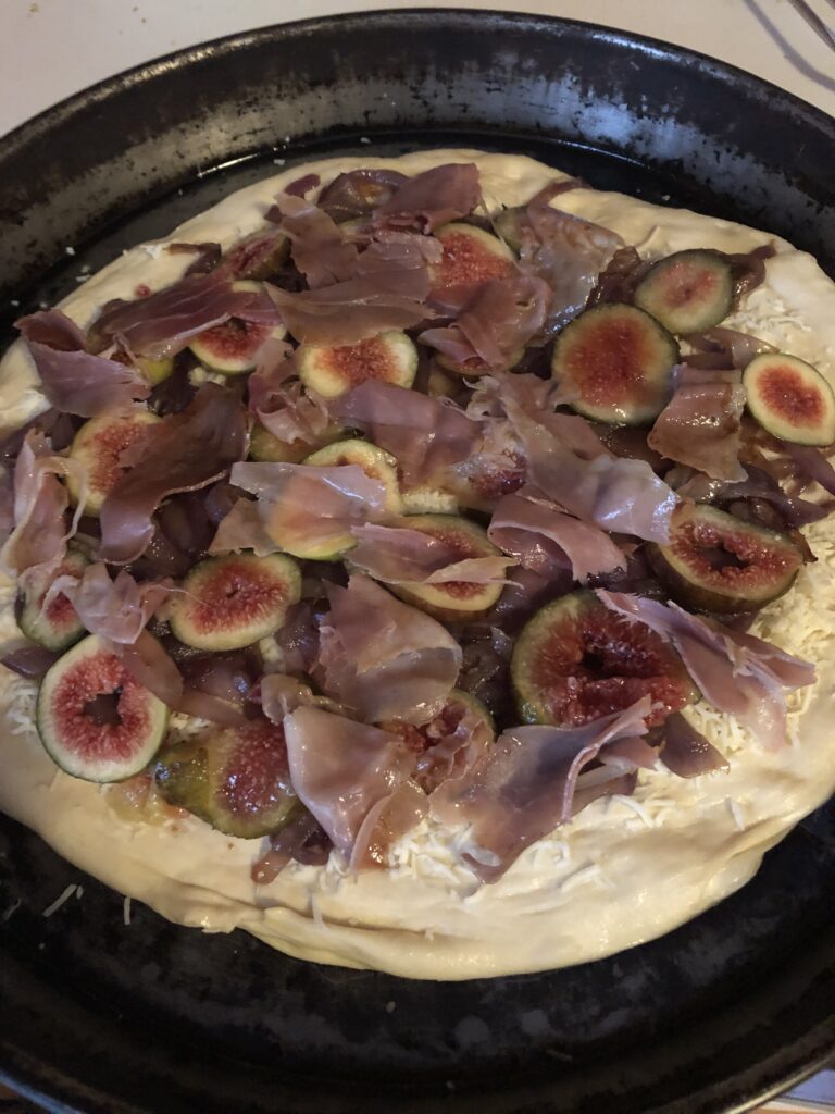 pizza dough in a pan with onions and figs on it