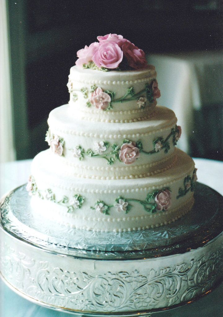 pink and green wedding cake with piped roses on tiers and vining green