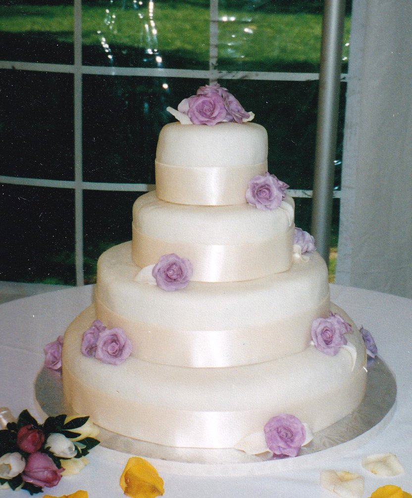 white wedding cake with ivory borders and lavender gumpaste roses