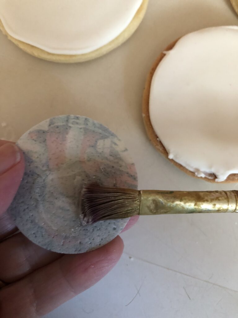 brushing corn syrup onto a wafer paper image for cookie decorating