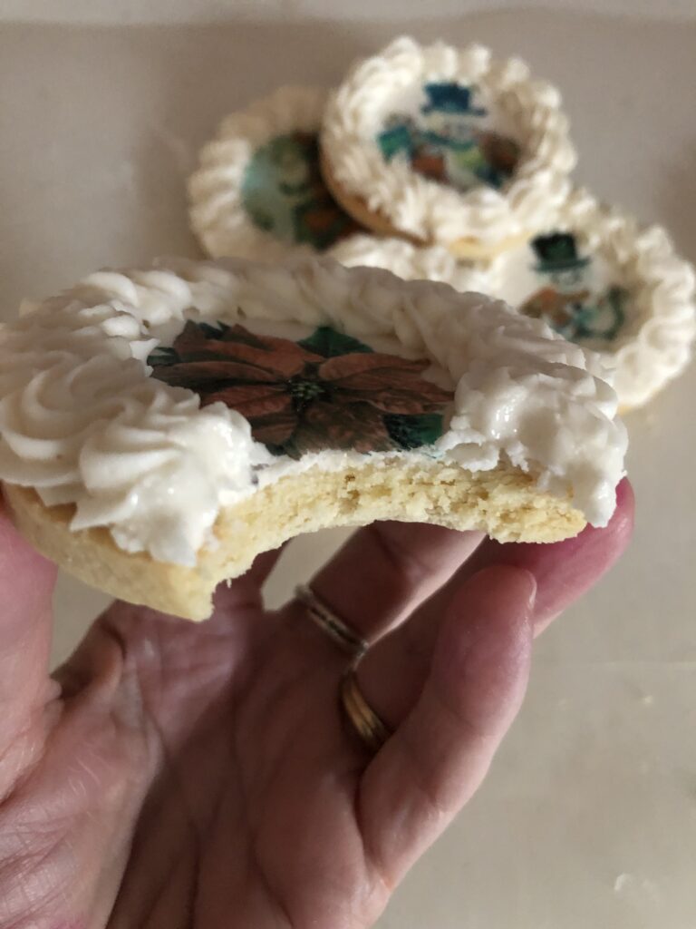 decorated cookies with wafer paper and royal icing borders with a bite taken out of it