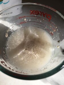 measuring cup with water and yeast in it