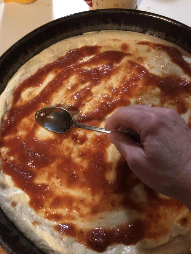 Spreading tomato sauce on the dough