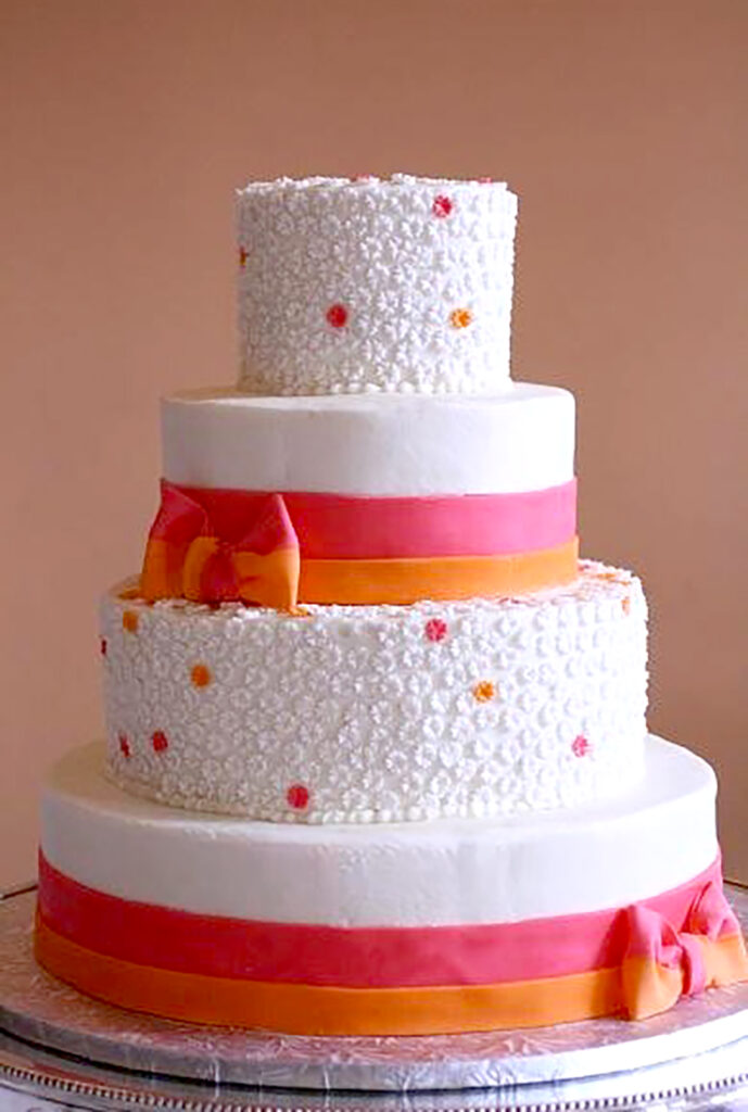 pink and orange wedding cake with tiny flowers and bows