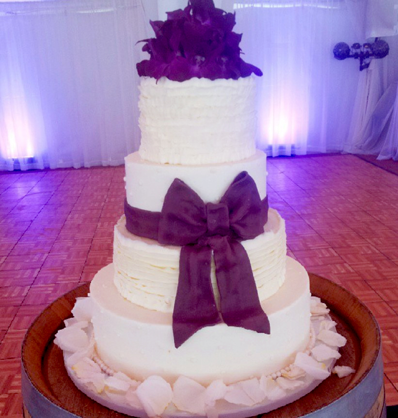 rustic wedding cake tiers with purple bow and flowers