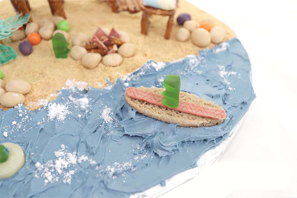 water icing and beach decorations made of candy on the beach themed gingerbread house