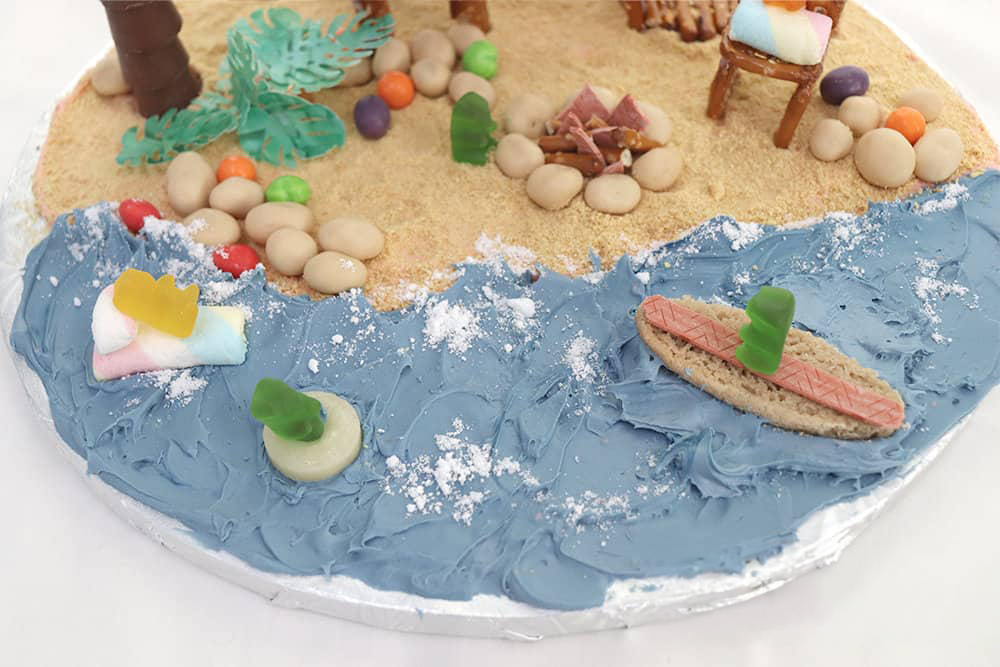 water icing and beach decorations made of candy on the beach themed gingerbread house
