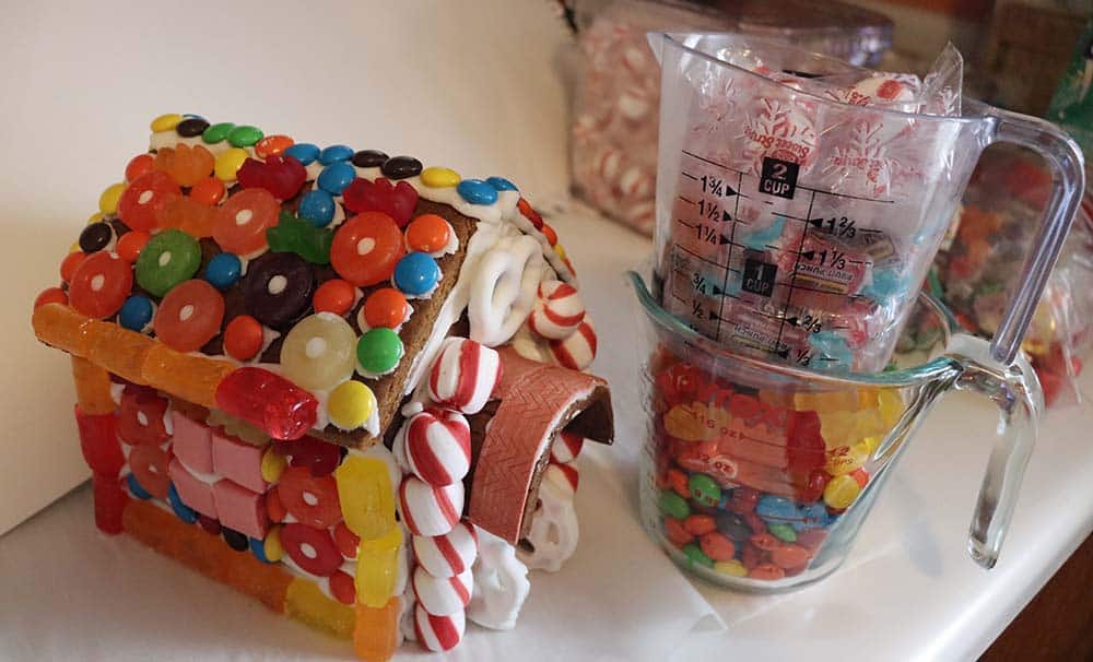 gingerbread house and measuring cups full of candy