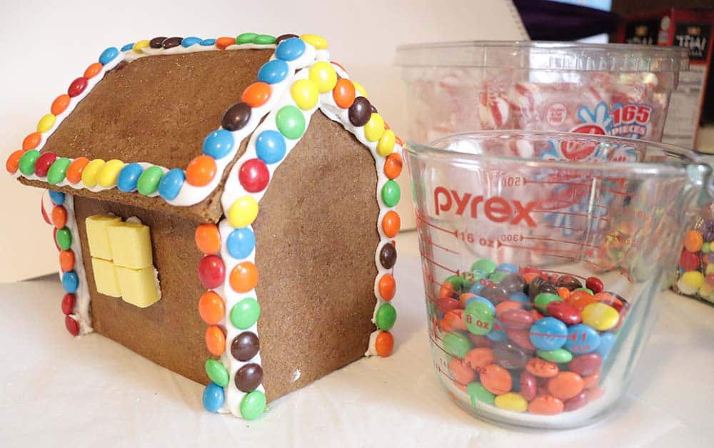 gingerbread house and a measuring cup with candy in it
