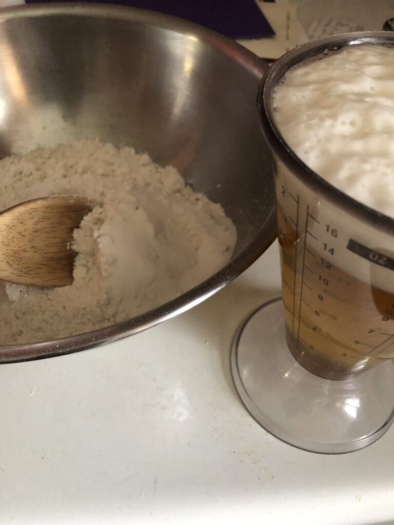beer in a measuring cup and a bowl with flour in it